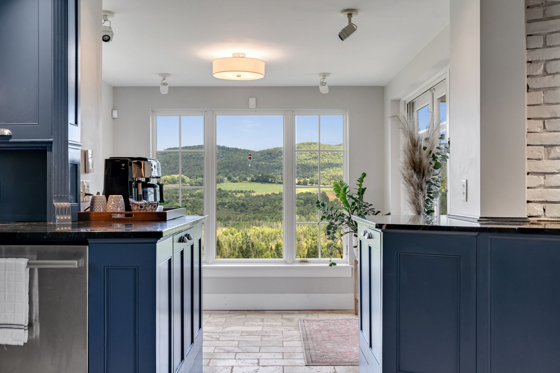 Kitchen with deep blue cabinets framing a window onto rolling Vermont hills